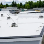 Completed white TPO and standing-seam metal roof at Legend Auto Sales in Puyallup, WA