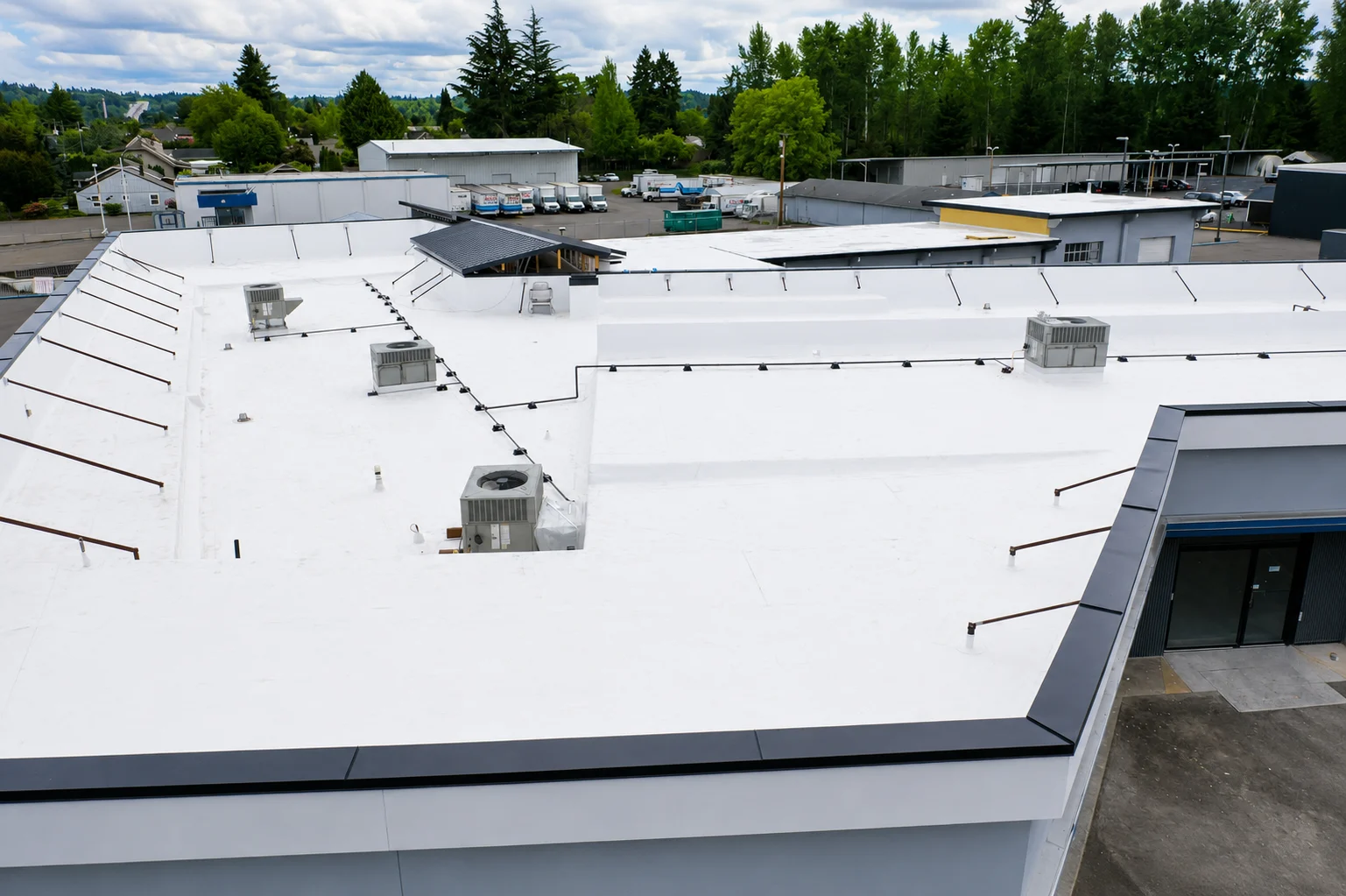 Completed white TPO and standing-seam metal roof at Legend Auto Sales in Puyallup, WA